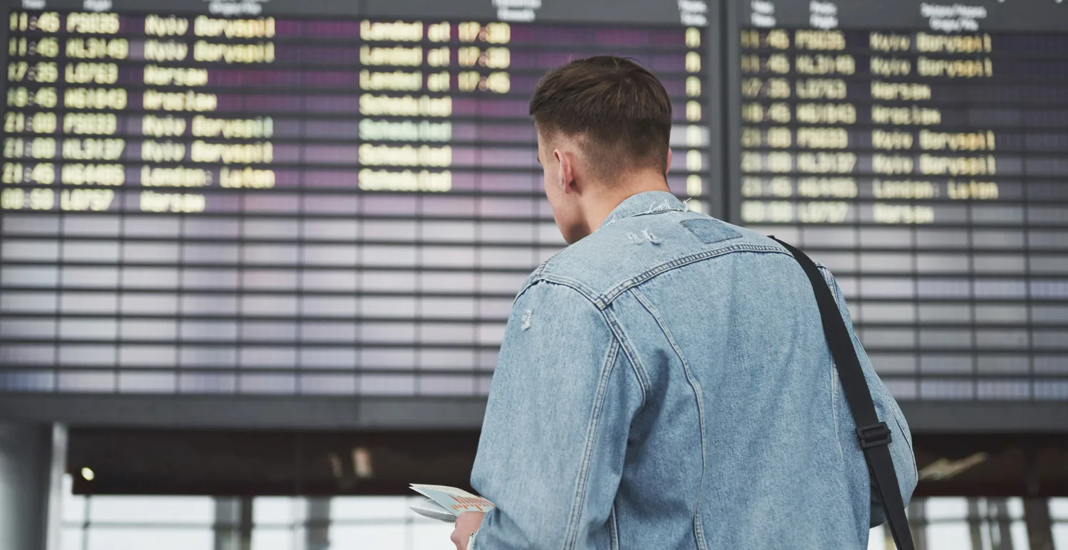 Essential English Phrases for Airport Conversations A Guide for a Smooth Trip. A man checking his flight schedule on the airport screen