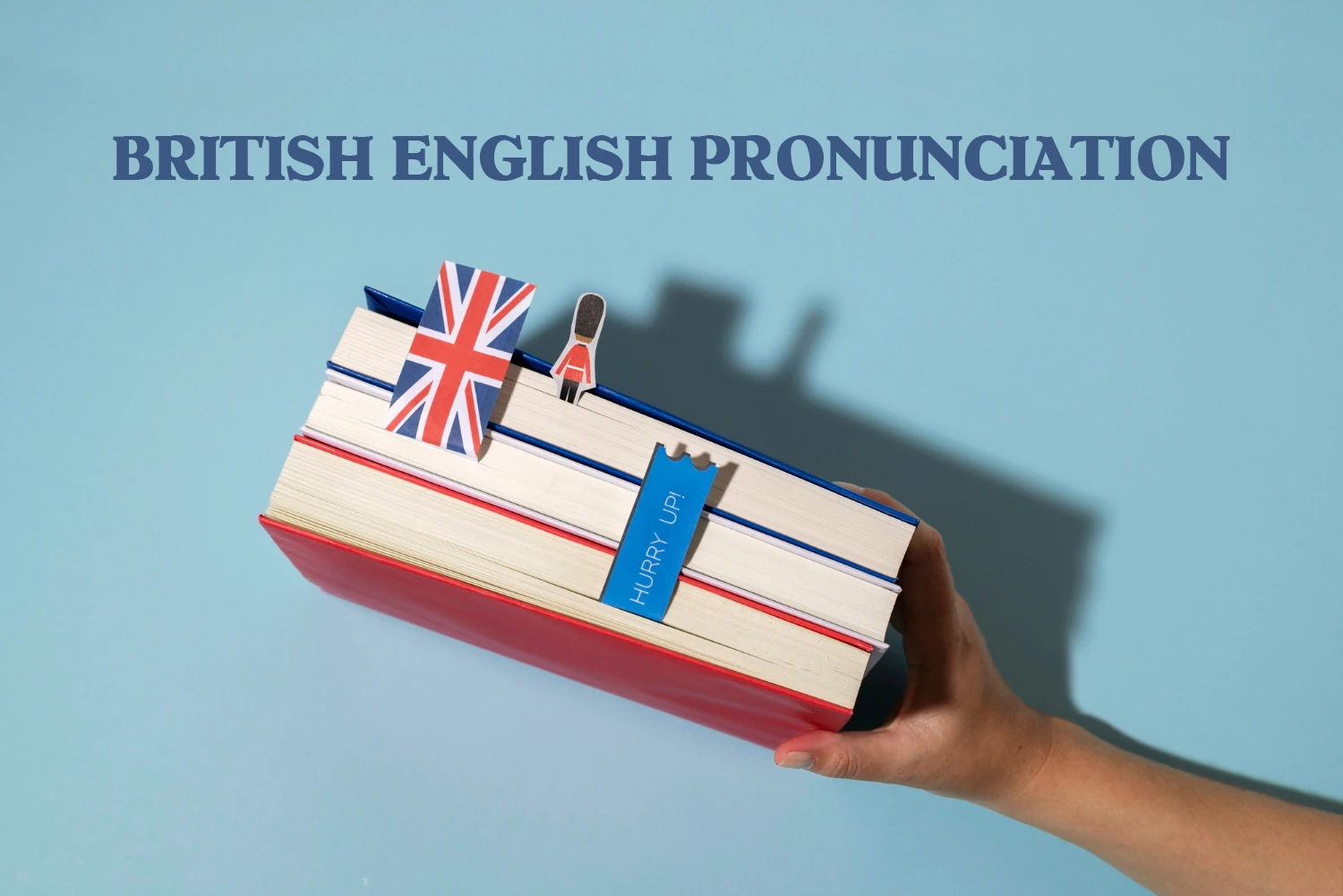 Practice British English Pronunciation Like a Pro , a photo of someone's hand holding a stacked books with British Flag